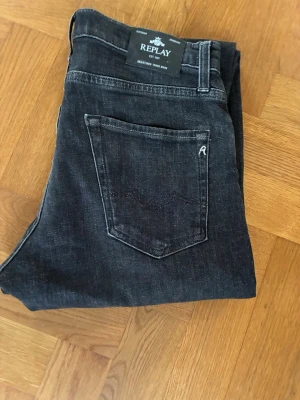 Svarta Replay jeans med raka ben - Snygga svarta jeans från Replay med raka ben och klassisk femficksmodell. Jeansen har diskreta slitningar och en liten logga på bakfickan. Tillverkade i mjukt denimtyg som ger en skön passform och stilren look.