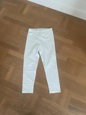 Vita leggings med hög midja - Snygga vita leggings med hög midja och stretchigt material. Perfekta för en clean och enkel look. De har en smal passform och resår i midjan för extra komfort. Passar till många olika stilar och är lätta att matcha.
