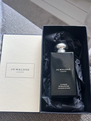 Jo Malone Cypress & Grapevine parfym (100 ml) - Helt ny parfym ifrån Jo Malone London i doften Cypress & Grapevine. Flaskan är svart med silverfärgad rund kork och har en stilren, rektangulär form. Kommer i originalförpackning med svart silkespapper för en lyxig känsla.