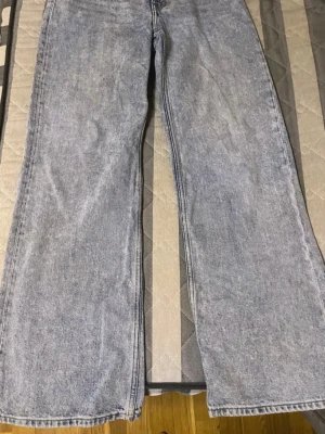 Ljusblåa vida jeans med rak passform - Säljer ett par ljusblåa jeans med rak och vid passform. Jeansen har klassisk femficksdesign och är tillverkade i denim med tvättad look. Perfekta för en avslappnad och trendig stil.