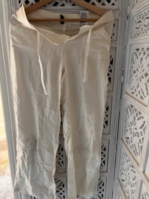 Beiga linnebyxor  - Säljer ett par beiga linnebyxor med snörning i midjan och knappstängning. Byxorna har raka ben och två framfickor, perfekta för en chill och avslappnad stil. Materialet är linne som känns luftigt och skönt. Köpt från HM säljer då de inte kommer till användning. Storlek Xs