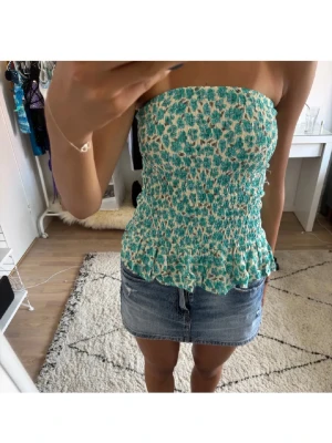 Blommig kortkjol med volangkant - Söt kortkjol med grönt och vitt blommönster och volangkant längst ner. Kjolen har en smickrande passform och är perfekt för varma dagar. Tillverkad i ett lätt och bekvämt material som passar till många olika stilar. Frifrakt till söndag 26 april