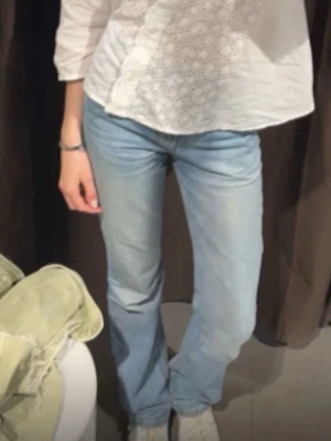 Ljusblå bootcut jeans - Säljer ett par ljusblå bootcut jeans med klassisk femficksmodell och hög midja. Jeansen har en lätt tvättad look och raka ben som går ut lite nedtill. Perfekta till sneakers eller boots för en avslappnad stil.