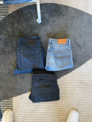 Tre par jeans i olika färger - Säljer tre par jeans i olika färger: ett par ljusblå klassiska jeans, ett par mörkblå och ett par svarta jeans. Alla har femficksmodell och raka ben. Perfekta för dig som vill ha basic jeans i garderoben. Märken och material framgår ej tydligt.
