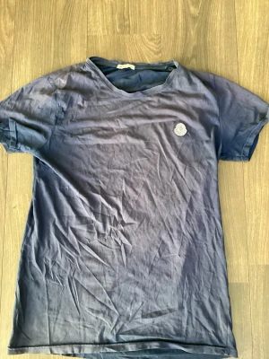Mörkblå Moncler t-shirt i bomull - Snygg mörkblå t-shirt från Moncler med klassisk passform och rund hals. T-shirten har korta ärmar och en liten Moncler-logga på bröstet. Tillverkad i mjuk bomull som känns skön mot huden. Perfekt till jeans eller shorts.