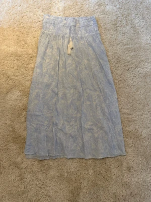 Ljusblå långkjol med mönster - Super söt lång kjol från Young Gina i storlek 170. Kjolen är 90 cl lång från midjan och ner. Använd två gånger. 