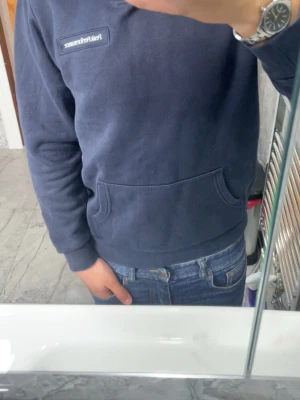 Mörkblå hoodie från Peak Performance - Säljer en mörkblå hoodie från Peak Performance med klassisk logotyp på bröstet. Hoodien har en stor magficka och ribbade muddar vid ärmslut och nederkant. Materialet är mjukt och fleecigt på insidan, perfekt för chill dagar.