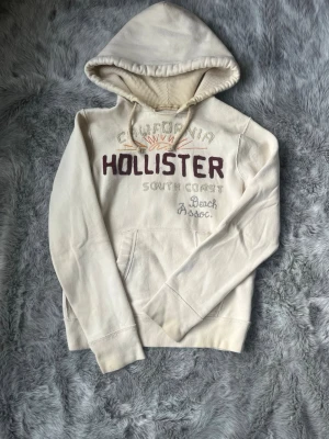 Vit hoodie från Hollister med tryck - Säljer denna sällsynta och mycket eftertraktade Hollister hoodie | Storlek S | Skick 9/10 | Vid eventuella frågor hör gärna av dig och erbjuder bra pris vid köp av bundle 😁✅