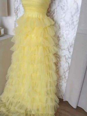 Finaste balklänningen  - Absolut finaste balklänningen i bandeau/axelbandslös modell och volanger i organza nertill. Köpt ny, men tyvärr för stor för dottern. Så drömmig och perfekt för dig som vill sticka ut på bal eller fest. Märke: Faeristy 