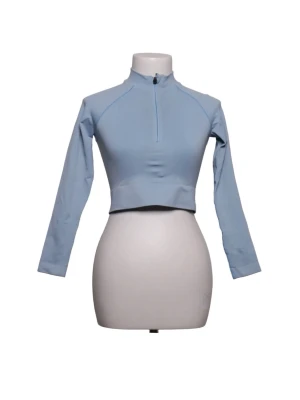 Ljusblå träningströja från TALA - Ljusblå långärmad träningströja från TALA med halv dragkedja framtill, kort i midjan. Tillverkad i en mjuk och stretchig bomullsblandning, perfekt för träning eller sportiga aktiviteter. Snygg och enkel design med diskreta sömmar.