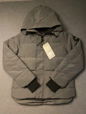 Canada Goose Macmillan Parka - Grå - Helt ny oanvänd Canada goose macmillan parka med väska storlek M. Med alla taggar och förpackning. Skriv ifall intresserad