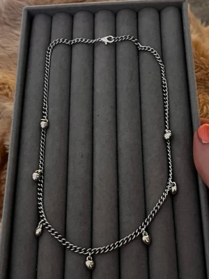 Silverfärgat halsband med droppar - Ett stilrent silverfärgat halsband med små droppformade hängen längs kedjan. Kedjan har en klassisk tvinnad design och stängs med ett karbinlås. Perfekt för dig som gillar minimalistiska smycken med en twist.