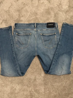 Blå jeans från Dondup - Snygga blå jeans från Dondup, tillverkade i Italien. Klassisk femficksmodell med raka ben och slitna detaljer för en avslappnad look. Jeansen har ljus tvätt och subtila kontrastsömmar. Perfekta för dig som gillar en casual och trendig stil.