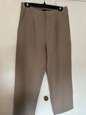Beige kostymbyxa från 157 - Stilrena beige kostymbyxor från 157 med rak passform och diskreta fickor. Byxorna har en klassisk midja och är tillverkade i ett slätt material. Jättefina på! Säljes då dom är för stora 🌸