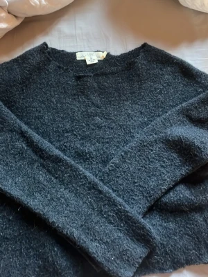 Mörkgrå klippt off shouldet stickad tröja i ullmix - Mysig mörkgrå stickad tröja från GAP i ull- och nylonmix. Tröjan har en enkel, rak passform med rund halsringning och långa ärmar. Perfekt för kalla dagar när du vill ha något både stilrent och bekvämt.