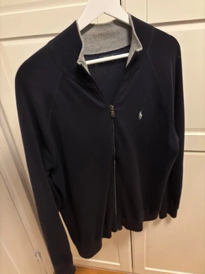 Mörkblå fullzip Ralph Lauren - En schysst full zip ifrån Ralph Lauren i storlek M. Priset är förhandlingsbart så det är bara att buda.