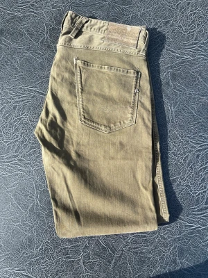 Bruna jeans från Replay - Snygga bruna jeans från Replay med klassisk femficksdesign och raka ben. Jeansen har en diskret logotyp på fickan och är tillverkade i ett mjukt bomullsmaterial med lite stretch för extra komfort. Perfekta för en avslappnad och stilren look. Modell anbass storlek W33 L30