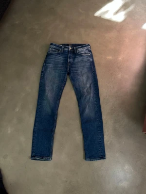 Blå jeans från Jack & Jones - Snygga blå jeans från Jack & Jones med klassisk femficksdesign och raka ben. Jeansen har en lätt tvättad look och detaljer i kontrastsömmar. Perfekta för en avslappnad och trendig stil.