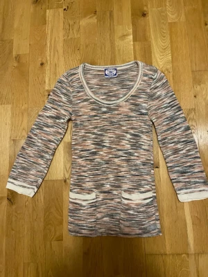 Kitty Hawk Stickad tröja i pastellfärger stl 36 - Mysig stickad tröja från  i en mix av beige, rosa och grå toner. Tröjan har rund halsringning, långa ärmar och två praktiska fickor framtill. Perfekt för lager-på-lager och chill dagar.