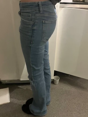 Ljusblå bootcut jeans med slitning - Säljer ett par ljusblå bootcut jeans med slitning vid knät. Jeansen har klassisk femficksmodell, normal midja och är tillverkade i mjukt denimtyg. Jag är 168 o den sitter bra i längden.