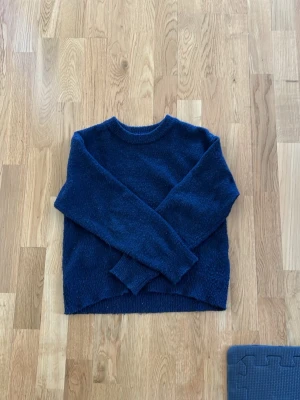 Mörkblå stickad tröja Gina Tricot - Mysig mörkblå stickad tröja från Gina Tricot i storlek 134/140. Tröjan har lång ärm och enkel, klassisk design som passar perfekt till både jeans och kjol. Materialet är mjukt och värmande, perfekt för kyligare dagar.