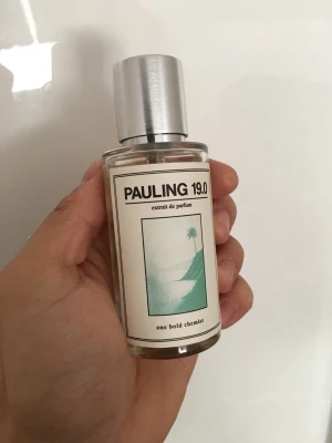 Pauling 19.0 Extrait de Parfum - Pauling 19.0 Extrait de Parfum i en stilren, cylindrisk glasflaska med silverfärgad metallkork. Etiketten har en minimalistisk design med grönt motiv av palmer och berg. Perfekt för dig som gillar unika och moderna dofter.