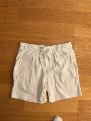 Vita shorts med snörning - Snygga vita shorts i mjuk frotté med snörning i midjan och fickor på sidorna. Perfekta för sommaren och chill dagar. Klassisk passform och enkel design som funkar till det mesta.