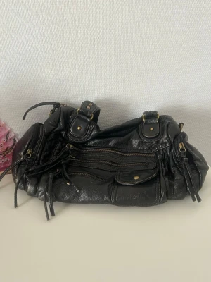 Svart läderväska  - Cool svart handväska i läder med flera dragkedjor och fickor framtill. Perfekt för dig som gillar en edgy och praktisk look med plats för allt du behöver. Axelremsa ingår! 🖤