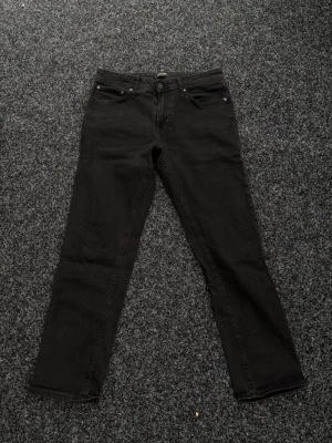 Svarta jeans från Jack & Jones - Säljer ett par svarta jeans från Jack & Jones, modell Regular Clark. Klassisk femficksdesign och rak passform. Perfekta till en avslappnad stil och funkar året runt. Jeansen är i ett mjukt och slitstarkt bomullsmaterial.
