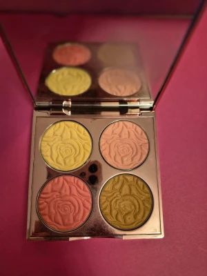 By Terry bronzerpalett med rosor - Bronzerpalett från By Terry med fyra pressade puder i nyanser av guld, persika, rosa och brons. Varje puder har ett detaljerat rosmönster och paletten har en spegel i locket. Lyxig guldfärgad förpackning med dekorativt mönster. Kan vara swatchad, testad någon gång.
