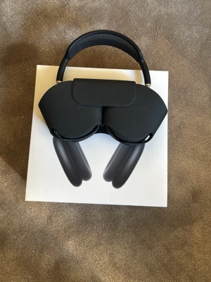 Apple AirPods Max Svart - Snygga Apple AirPods Max i svart med elegant aluminiumdesign och mjuka öronkuddar. Over-ear-modell med justerbart huvudband i mesh för extra komfort. Levereras med originalförpackning och smart skyddsfodral.