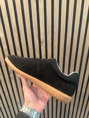 Svarta sneaker maison  - Stilrena svarta sneakers med ovandel i mocka och klassisk brun gummisula. Lågt skaft och svarta skosnören. Insidan är vit för en snygg kontrast. Perfekta för dig som gillar minimalistisk och tidlös stil.