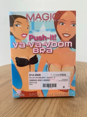 Svart push-up bh från Magic Bodyfashion - Svart push-up bh från Magic Bodyfashion, modell Va-Va-Voom Bra. Axelbandslös och rygglös design med snörning framtill för extra push och form. Perfekt under plagg med bar rygg eller axlar. Tillverkad i syntetmaterial.