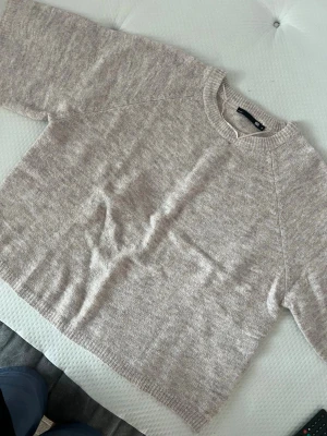Beige stickad tröja - Beige stickad tröja från 157 med korta ärmar och rund halsringning. Tröjan har en avslappnad passform och ribbstickade detaljer vid hals, ärmslut och nederkant. Perfekt för lager-på-lager och enkel att matcha med olika outfits.😋💞