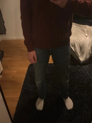 Mörkröd kabelstickad tröja Gant - Säljer en mörkröd kabelstickad tröja från Gant med rund halsringning och diskret logga på bröstet. Tröjan har långa ärmar och är perfekt för dig som gillar klassisk och stilren design. Passar till både jeans och chinos.
