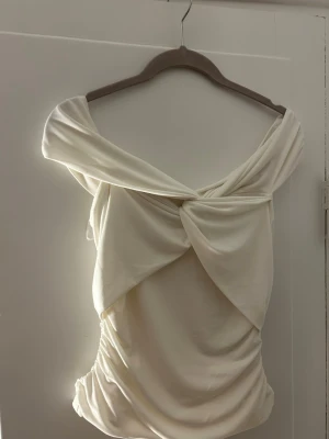 Offshoulder cremevit omlotttopp! - Trendig cremevit topp med offshoulder-design och snygg omlott-detalj framtill. Toppens tyg är mjukt, men inte så stretchigt. Superfin topp som är lätt att styla å får outfiten att se elegant och stilren ut! 💞 Toppen är i bra skick då den bara är använd enstaka gånger! 