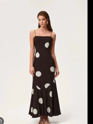 Brun adoore klänning med stora prickar - Brun långklänning med tunna axelband och stora vita prickar. Klänningen har en figurnära passform upptill och faller snyggt längs kroppen. Den slutsålda klänningen från adoore. Finns inte längre att köpa på hemsidan. Helt ny med prislapp på.