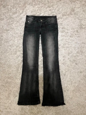 Svarta cheap monday jeans - Säljer ett par svarta bootcut jeans med tvättade detaljer på benen. Jeansen har låg midja, klassisk femficksmodell och stängs med knapp och dragkedja. Perfekta för en trendig och avslappnad look. Jag har sprättat bort den lilla lappen med döskalle från baksidan( kolla bild 5) men de ser ut som nya❤️ 