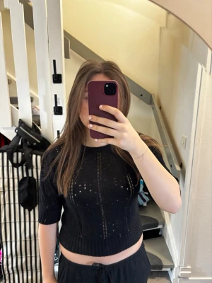 Svart stickad kortärmad tröja NA-KD - Svart stickad tröja från Gina Tricot med korta ärmar och ribbad nederkant. Tröjan har ett genombrutet mönster och är croppad i modellen. Perfekt för lager-på-lager och snygg till både jeans och kjol.💖