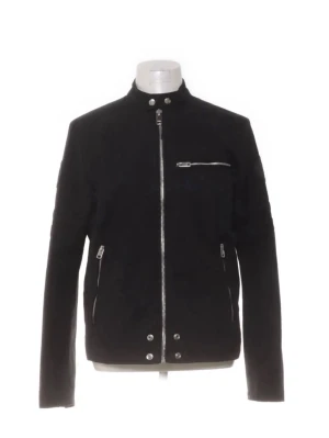 Svart Diesel jacka med dragkedjor - Stilren svart bikerjacka med ståkrage och silverfärgade dragkedjor framtill, på fickor och ärmslut. Jackan har tryckknappar vid kragen och nederkanten samt en bröstficka med dragkedja.