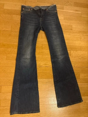 Mörkblå  lågmidjade bootcut jeans med rå kant - Snygga mörkblå bootcut jeans med lätt slitning och rå, fransad midjekant. Klassisk femficksmodell i stretchigt denimtyg. Perfekta för en avslappnad och trendig look. Stolek S. Längden är perfekt för mig som är 170cm.  Använd 1 gång. Priset går att diskutera. Frakt ingår ej!