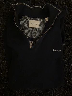 Marinblå quarter zip från GANT - Snygg marinblå tröja från GANT med halvzip. Materialet är mjukt och stretchigt mer mot kashmir/merino hållet. Tröjan har ett litet hål vid armhålan som såklart inte syns vid användning. Hör av er vid några frågor!😁