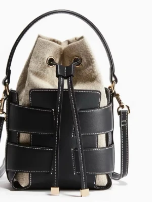 Svart och beige bucket bag  - Trendig bucket bag med svart läderimitation och beige canvas. Väskan har justerbar axelrem, handtag och snygga guldfärgade detaljer. Stängs med dragsko och har kontrastsömmar som ger en cool look. Perfekt för dig som vill ha en unik och stilren handväska.