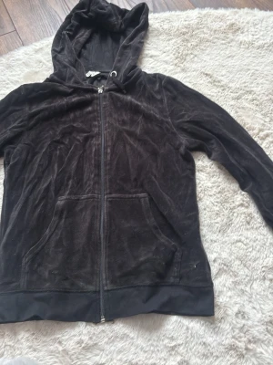 Svart velourhoodie med dragkedja - Mysig svart hoodie i mjuk velour från Cubus. Tröjan har dragkedja framtill, två fickor och en huva med snören. Perfekt för en chill och avslappnad stil.