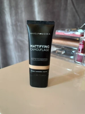 Makeup Mekka Mattifying Foundation - Mattifying Camouflage Matte Foundation från Makeup Mekka i färgen Neutral Fair 02. Flytande foundation i svart tub, ger full täckning och passar normal, kombinerad och oljig hud. Innehåller antioxidanter och mineraler som återfuktar och vårdar huden.