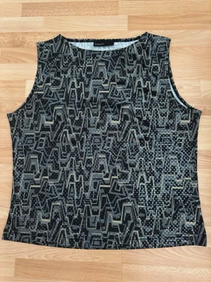 Fest Svart/grå  linnetopp  - Cool ärmlös linnetopp  med svart bas och abstrakt geometriskt mönster i grått och beige samt prickar över hela tyget. Perfekt för dig som gillar unika prints och vill sticka ut lite extra. Använd en gång.