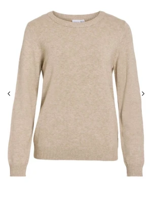 Beige stickad tröja från VILA - Klassisk beige stickad tröja från VILA med rund halsringning och ribbade muddar vid ärmslut och nederkant. Tröjan har en enkel och stilren design, perfekt för lager på lager och passar till det mesta. Materialet ser mjukt och bekvämt ut. Köparen står för frakten
