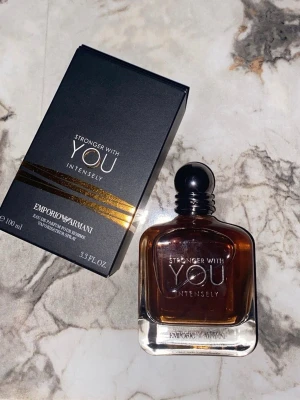 Emporio Armani Stronger With You Intensely - Stronger With You Intensely från Emporio Armani är en herrparfym i en stilren, mörkbrun glasflaska med svart rund kork. Förpackningen är svart med eleganta guldlinjer och vit text. Flaskan innehåller 100 ml Eau de Parfum.