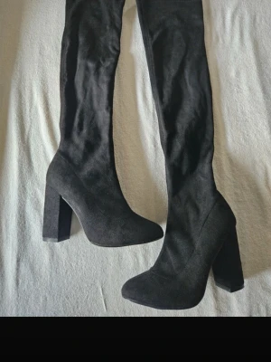 Svarta overknee stövlar med klack - Ett par klackar i mockaimitation från NLY shoes. Köpte inför halloween från en annan tjej här på vinted. OBS alla bilder är hennes, förutom sista som visar min olycka. Hoppade av min VOI och det blev ett litet hål på högra skon😆🤝