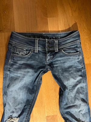 Lågmidjade jeans från Freesole - Säljer ett par blå jeans från Free Soul med slitningar och snygg tvätt. Jag har sytt ut dem själv💞Jeansen har tre knappar i midjan, klassiska fem fickor och dekorativa sömmar på bakfickorna. Materialet är denim med en cool, använd look.säljer pga för små för mig. Storlek 26/32